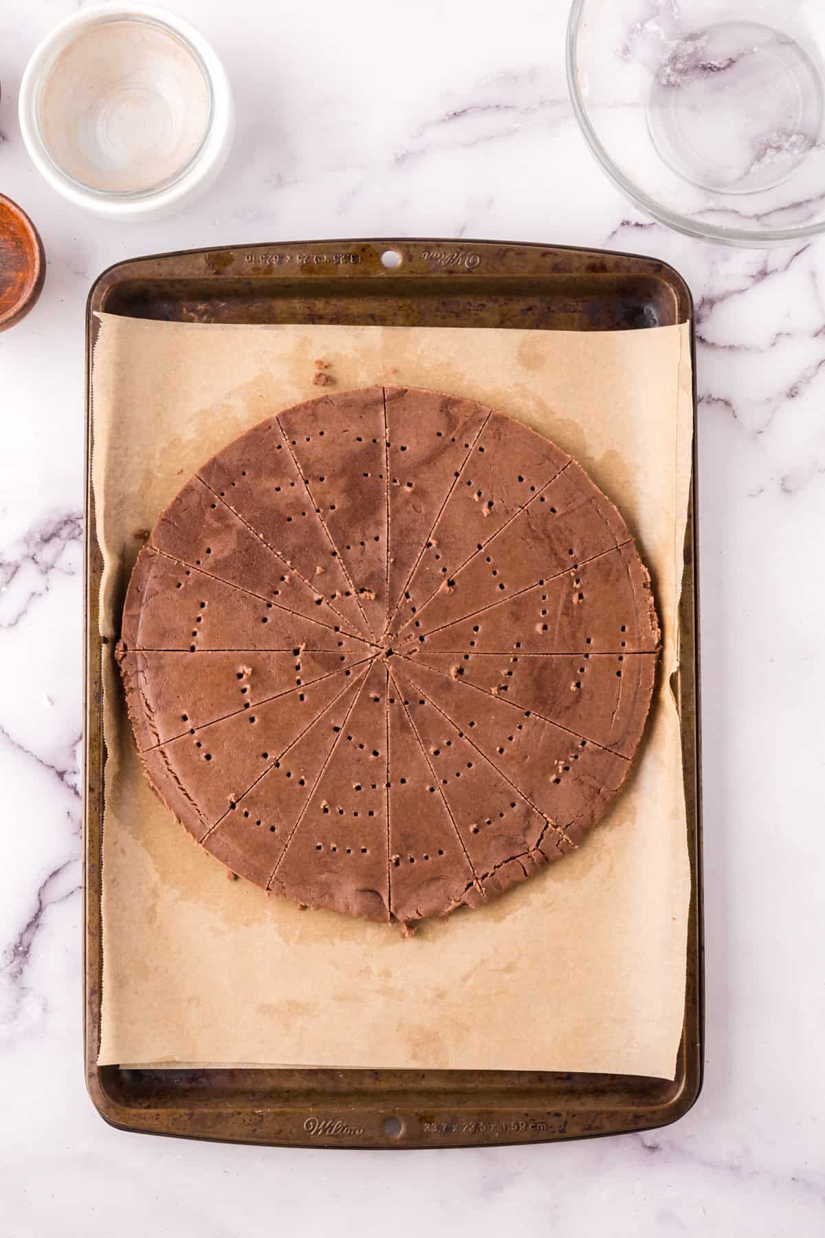 baking sheet with parchment with unbaked chocolate shortbread.