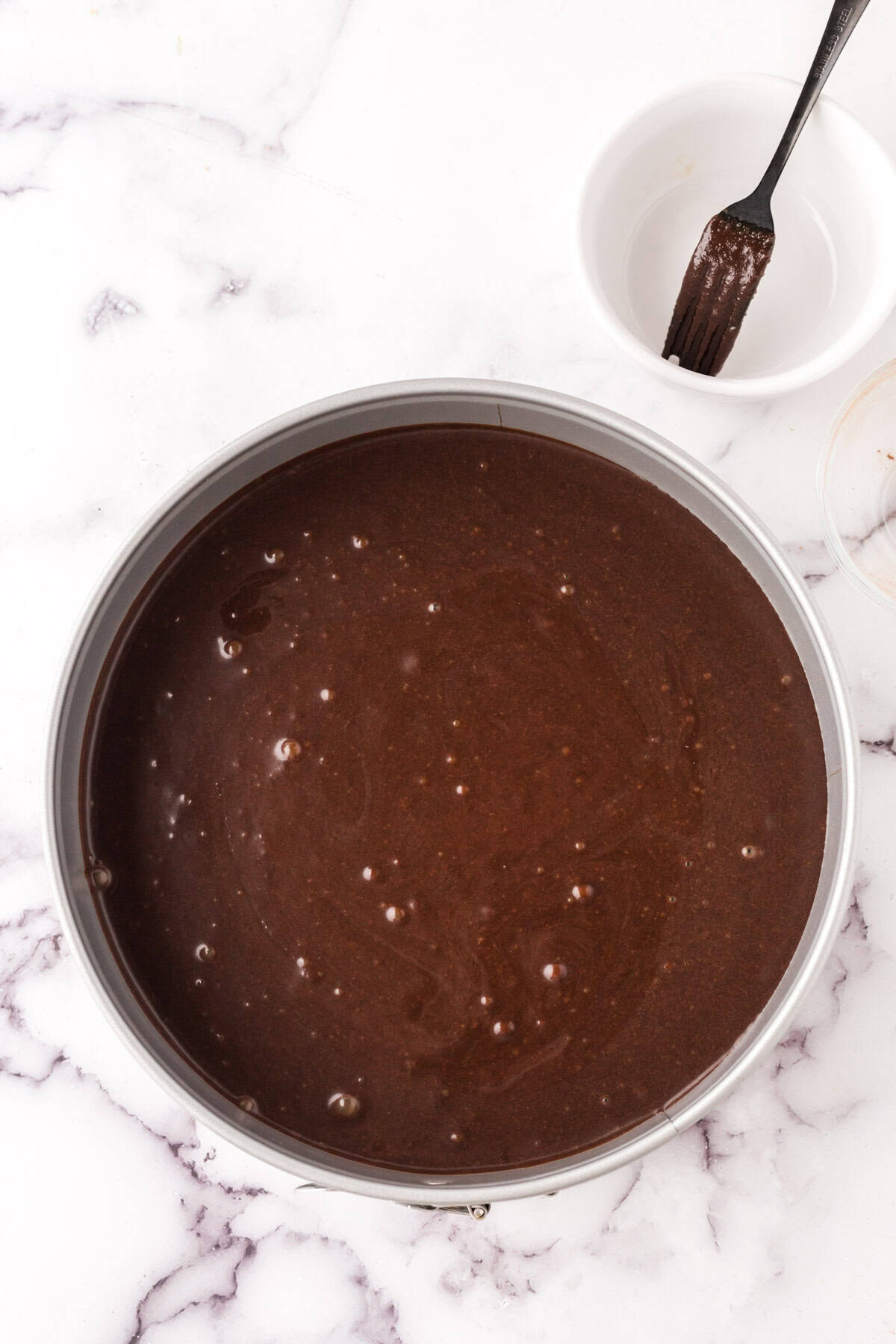 round cake pan with raw flourless chocolate cake batter ready to bake.