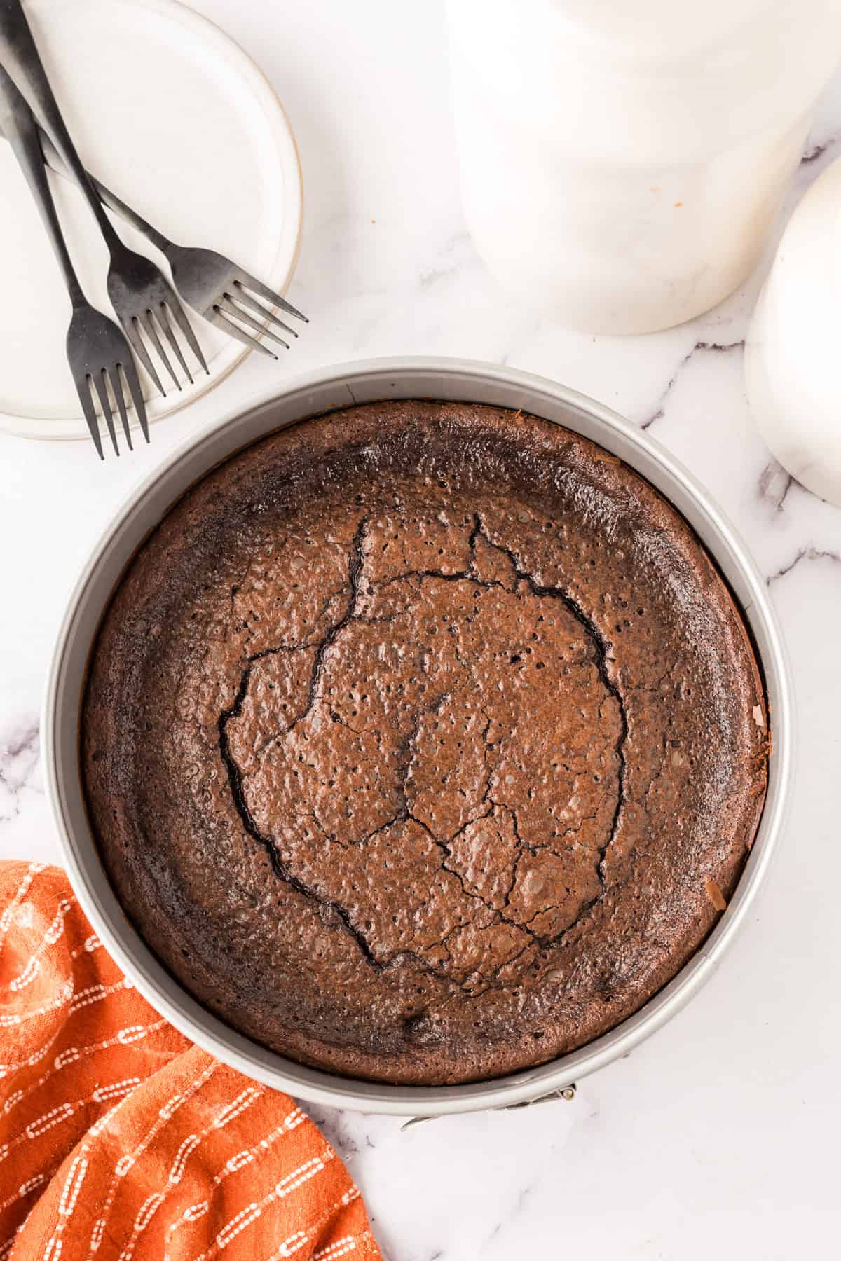 round cake pan with fresh from the oven flourless chocolate cake.