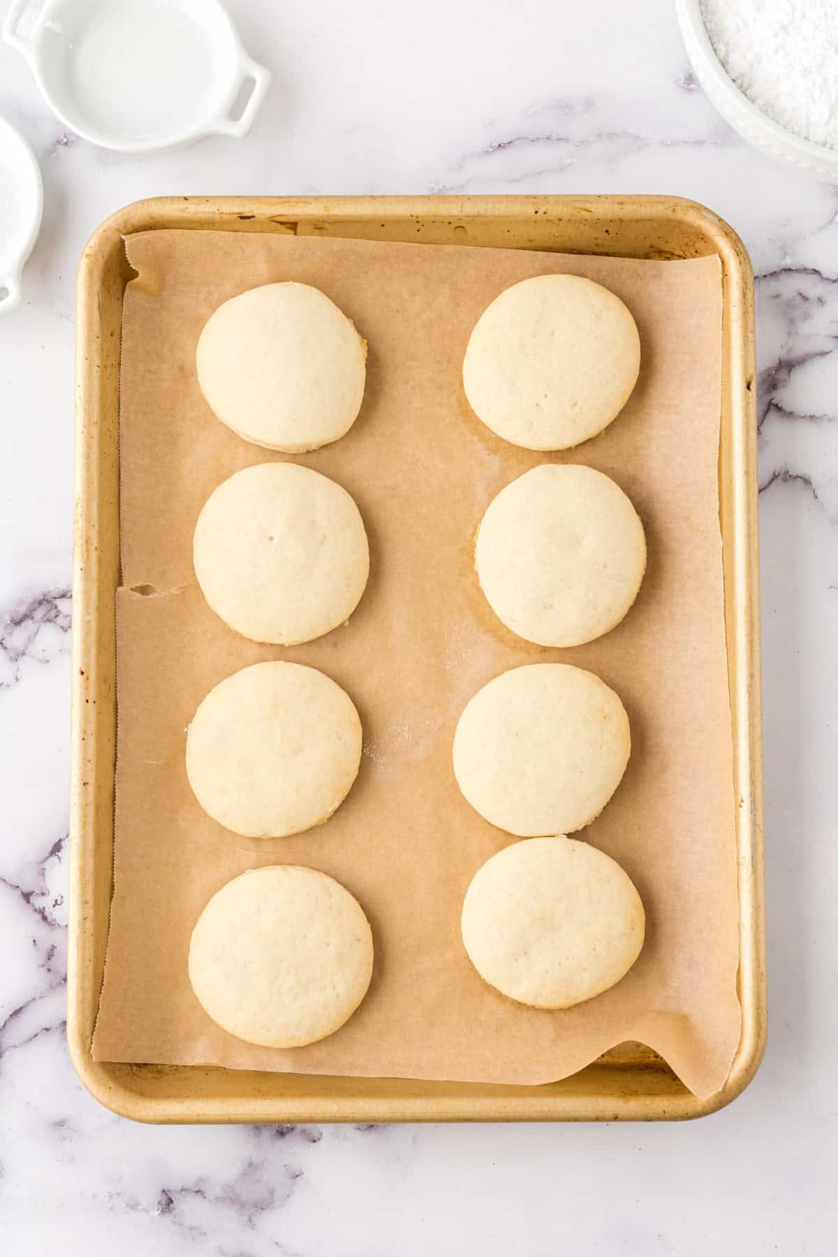 fruit pizza cookies without any toppings on parchment on a half sheet pan.