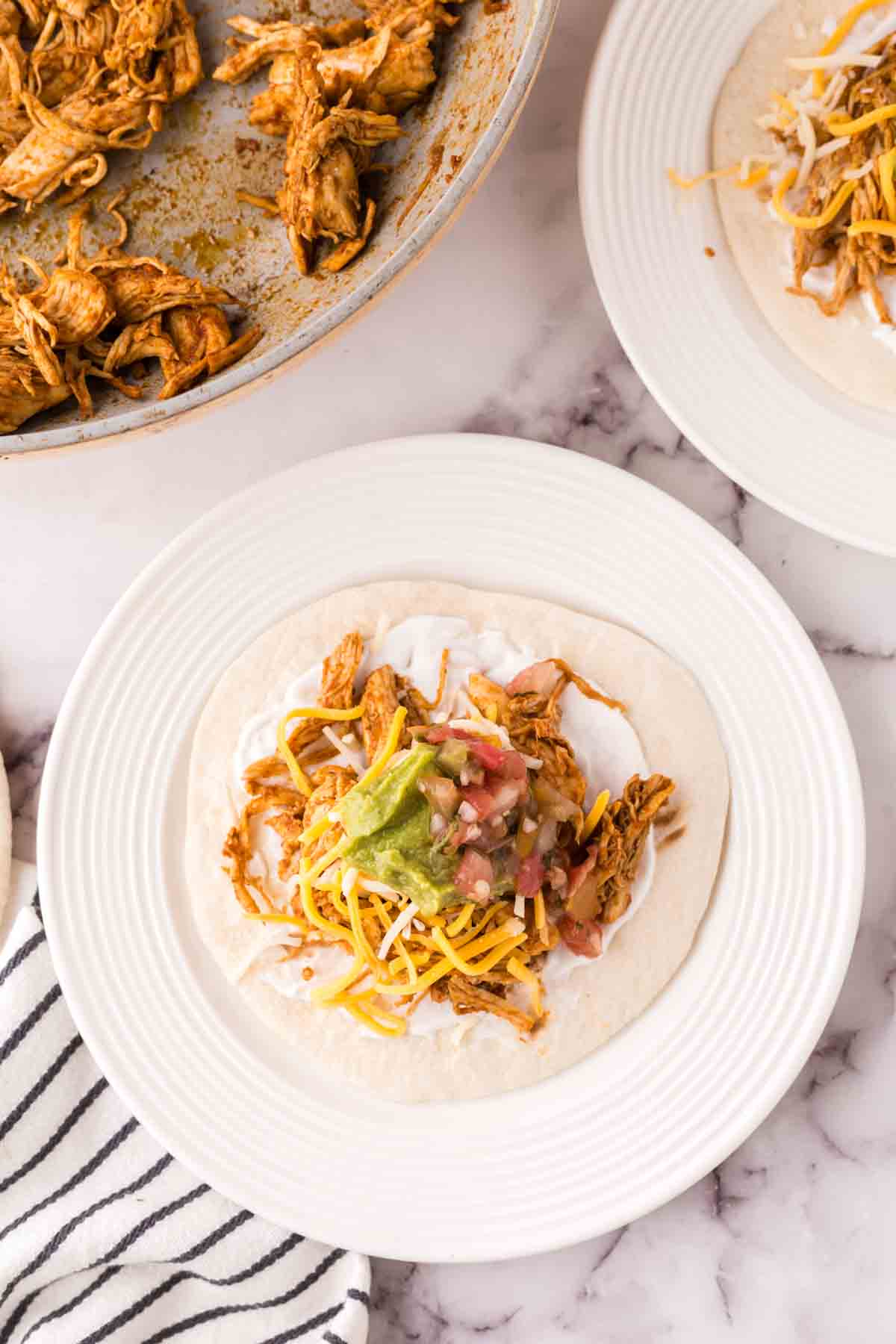 shredded chicken on a tortilla making a taco.
