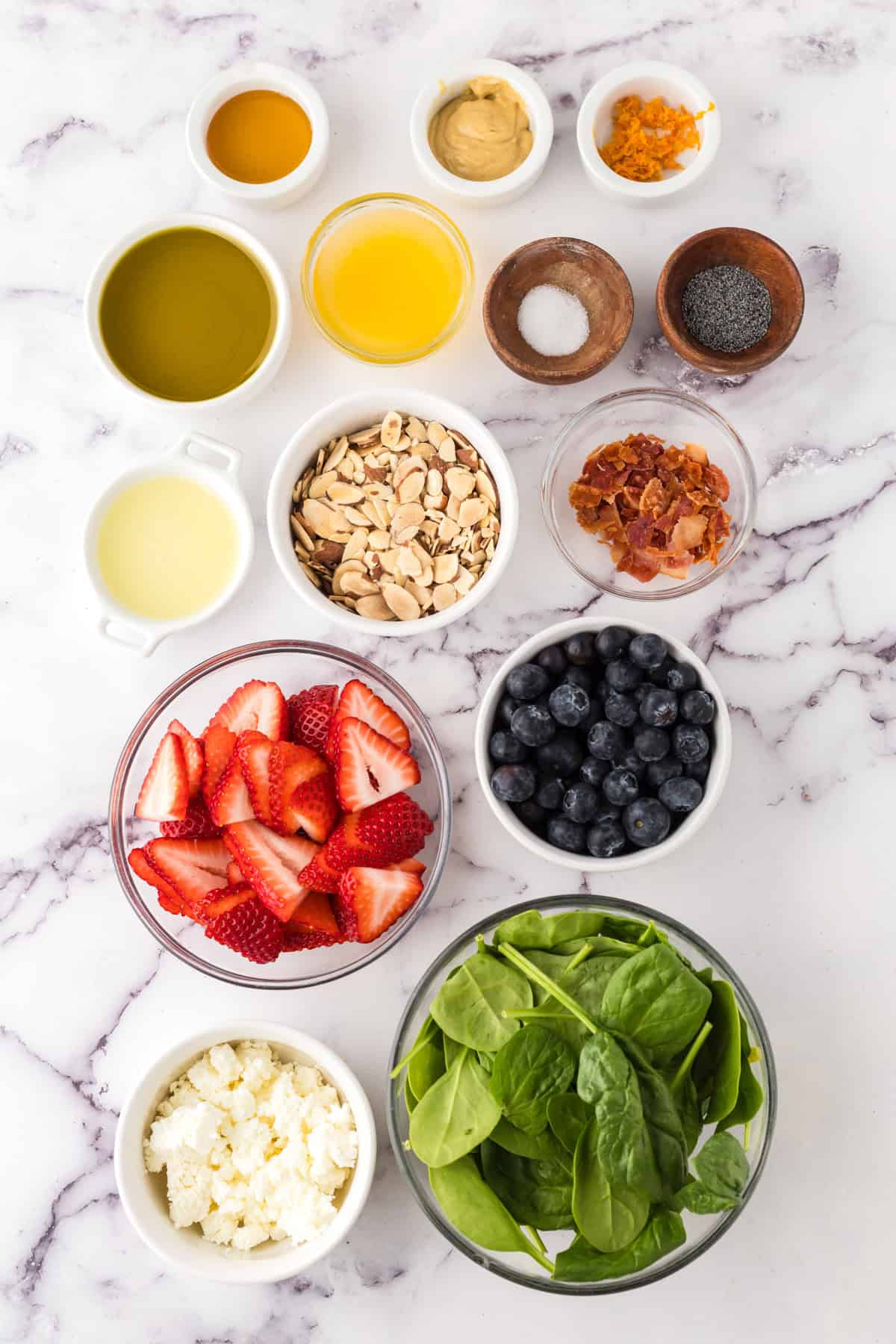 portion bowls each with raw ingredients to make spinach berry salad