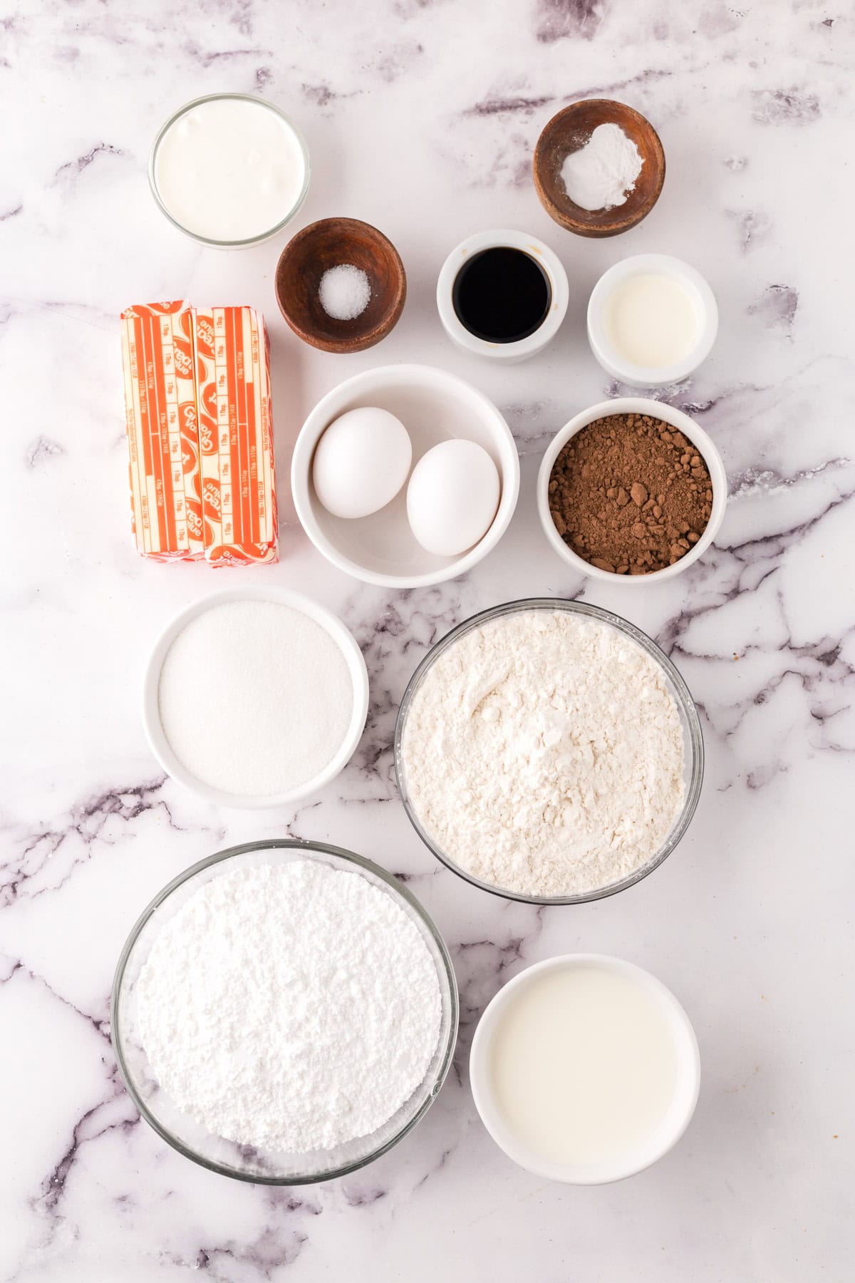 portion bowls each with raw ingredients to make vanilla cupcakes with chocolate frosting.