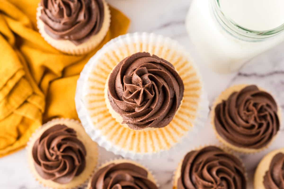 vanilla cupcakes with chocolate frosting on an ornate stand.