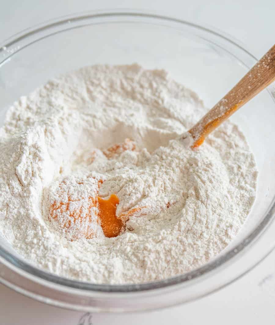 Clear glass mixing bowl in the process of making cassava flour and sweet potato tortilla dough.