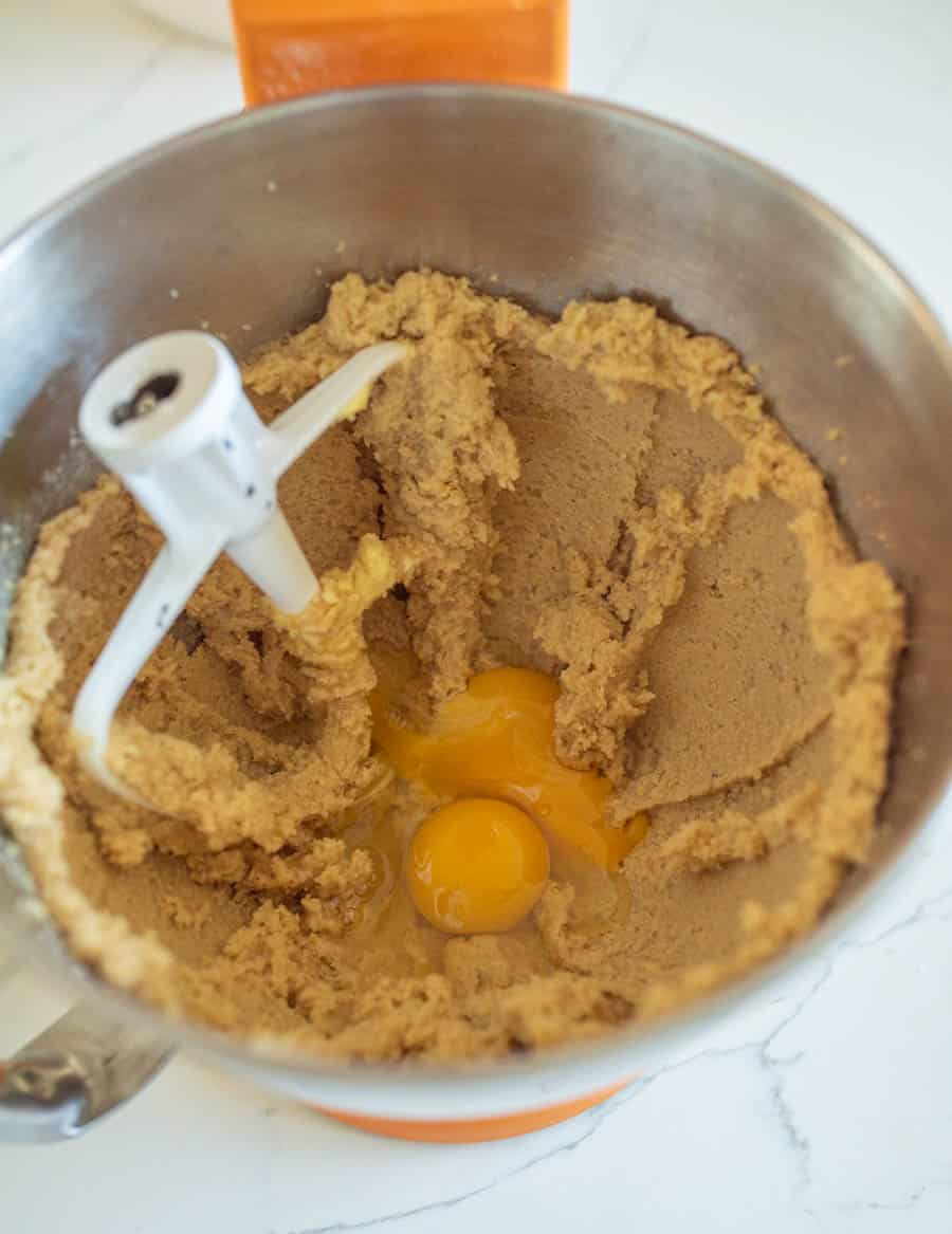 Dark chocolate Halloween M&M Cookie dough in a mixing bowl with the eggs and vanilla added.