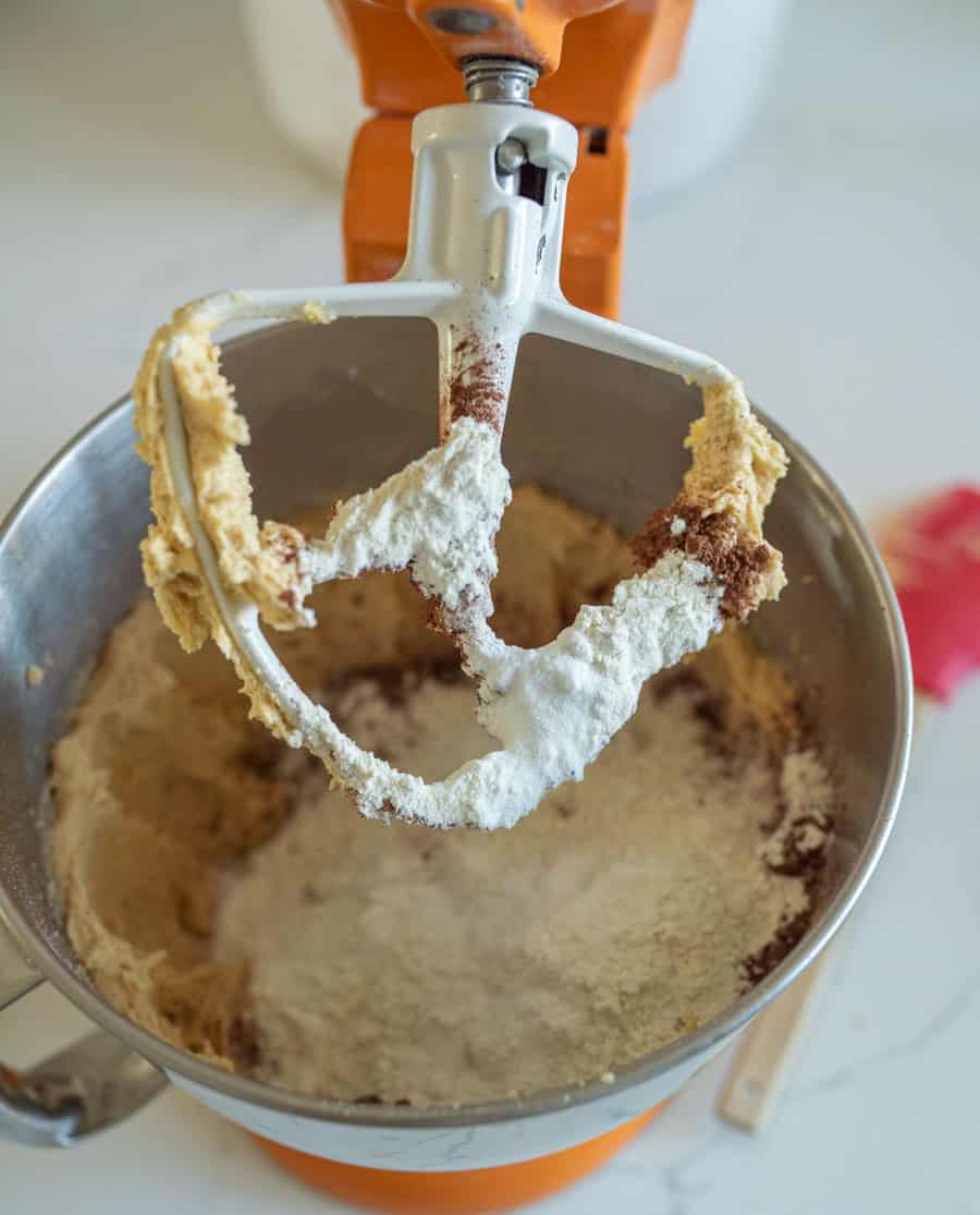 Dark chocolate Halloween M&M Cookie dough in a stand mixer with the dry ingredients added.