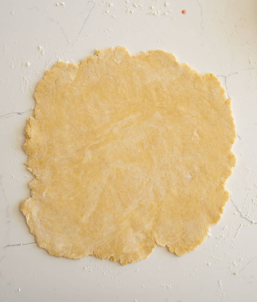 An evenly rolled out pie crust on a white counter.