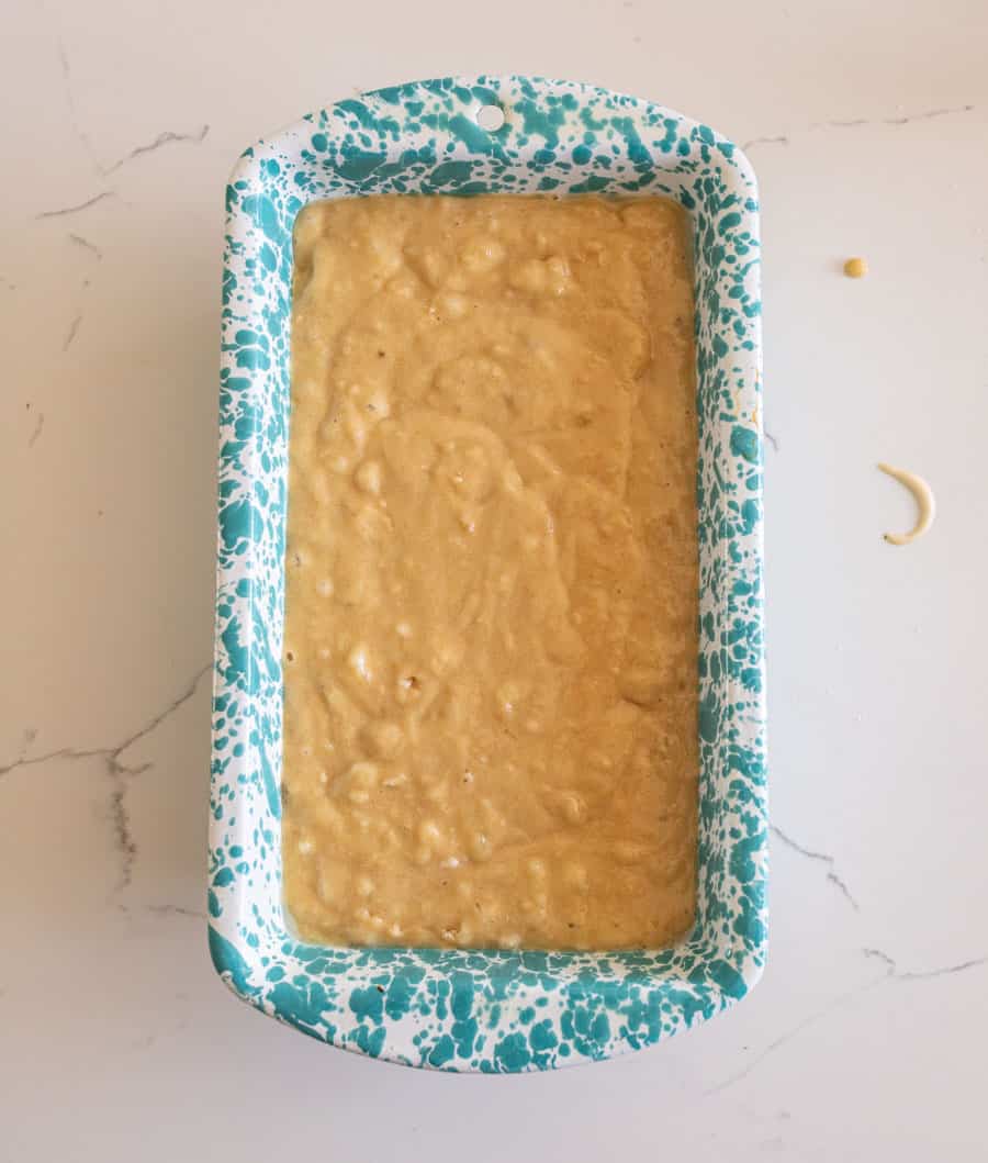 Sourdough banana bread batter in a blue and white speckled enamelware pan on a white counter.