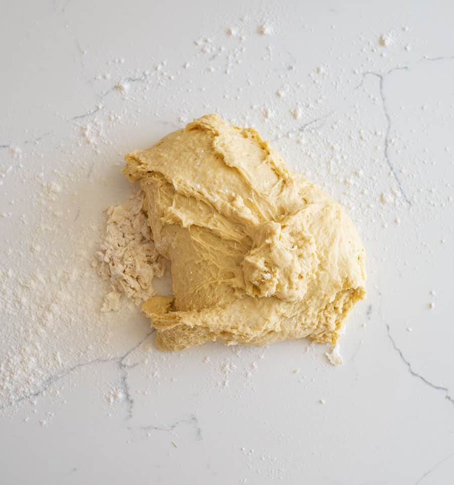 Sourdough hamburger bun dough on a lightly floured white counter.
