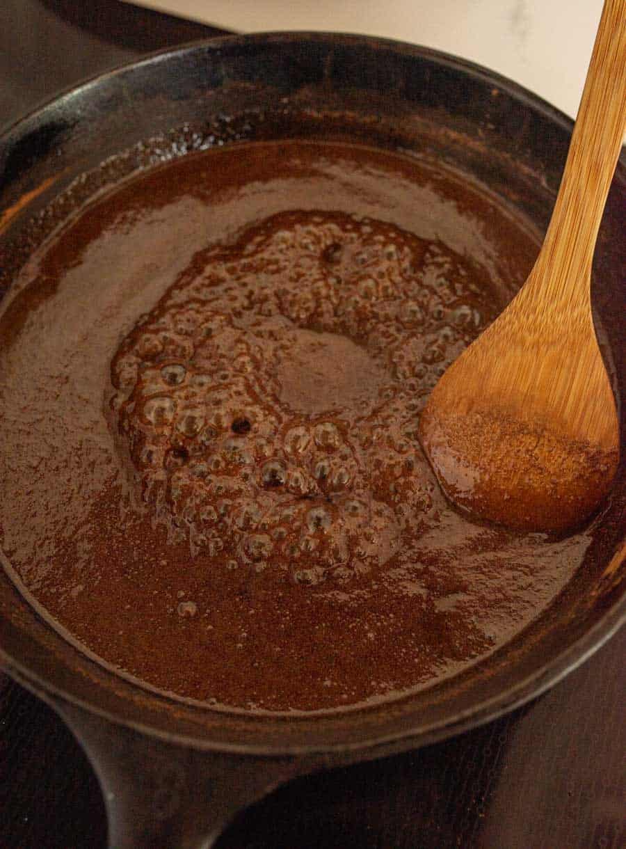The sugary sauce bubbling in a cast iron pan.