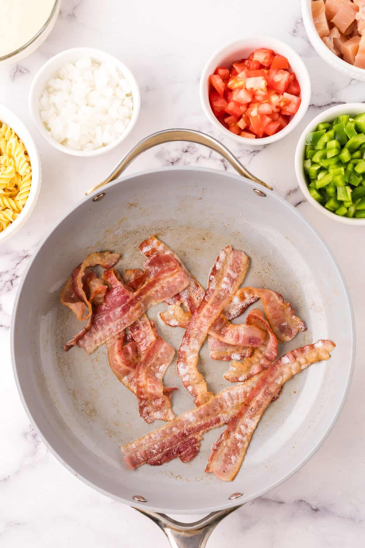 sautéed pan in the process of making creamy chicken bacon pasta.