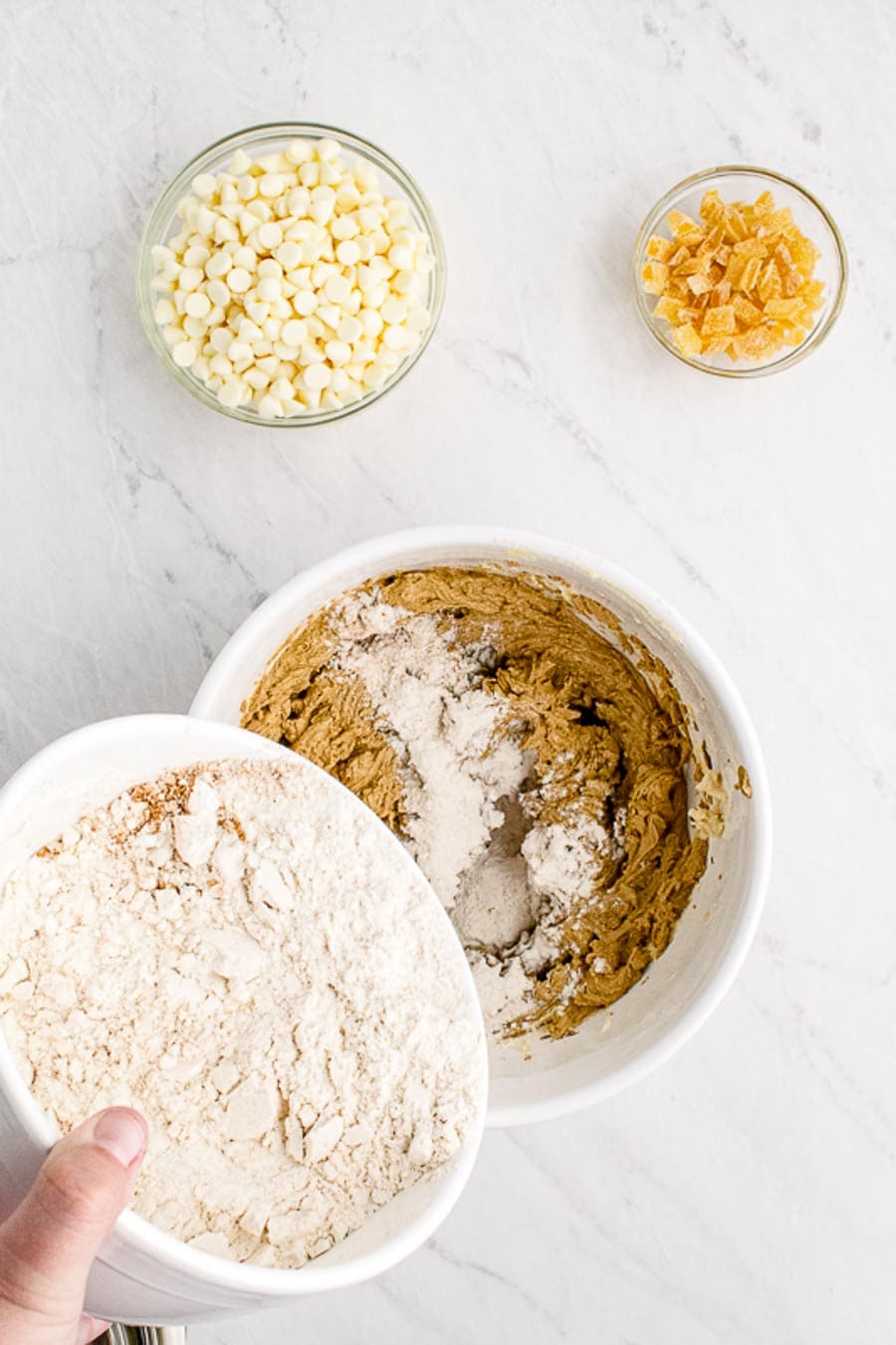 Dry ingredients being added to the white mixing bowl in the process of making gingerbread blondie batter.