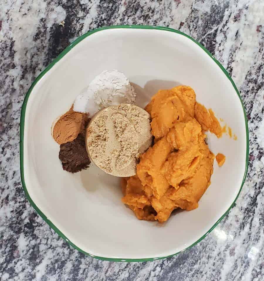 Ingredients in a white bowl with a green rim for mini pumpkin pies.