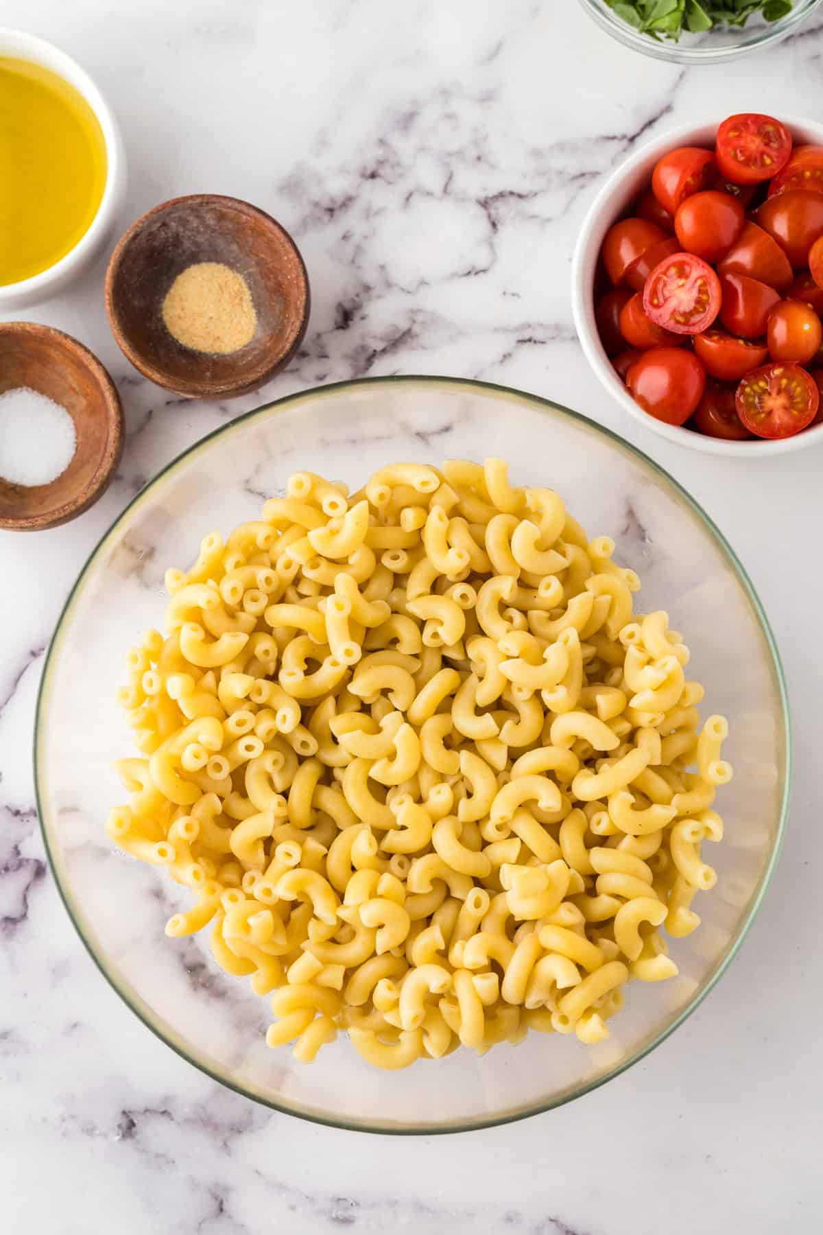 clear mixing bowl in the process of making Italian Pasta Salad.