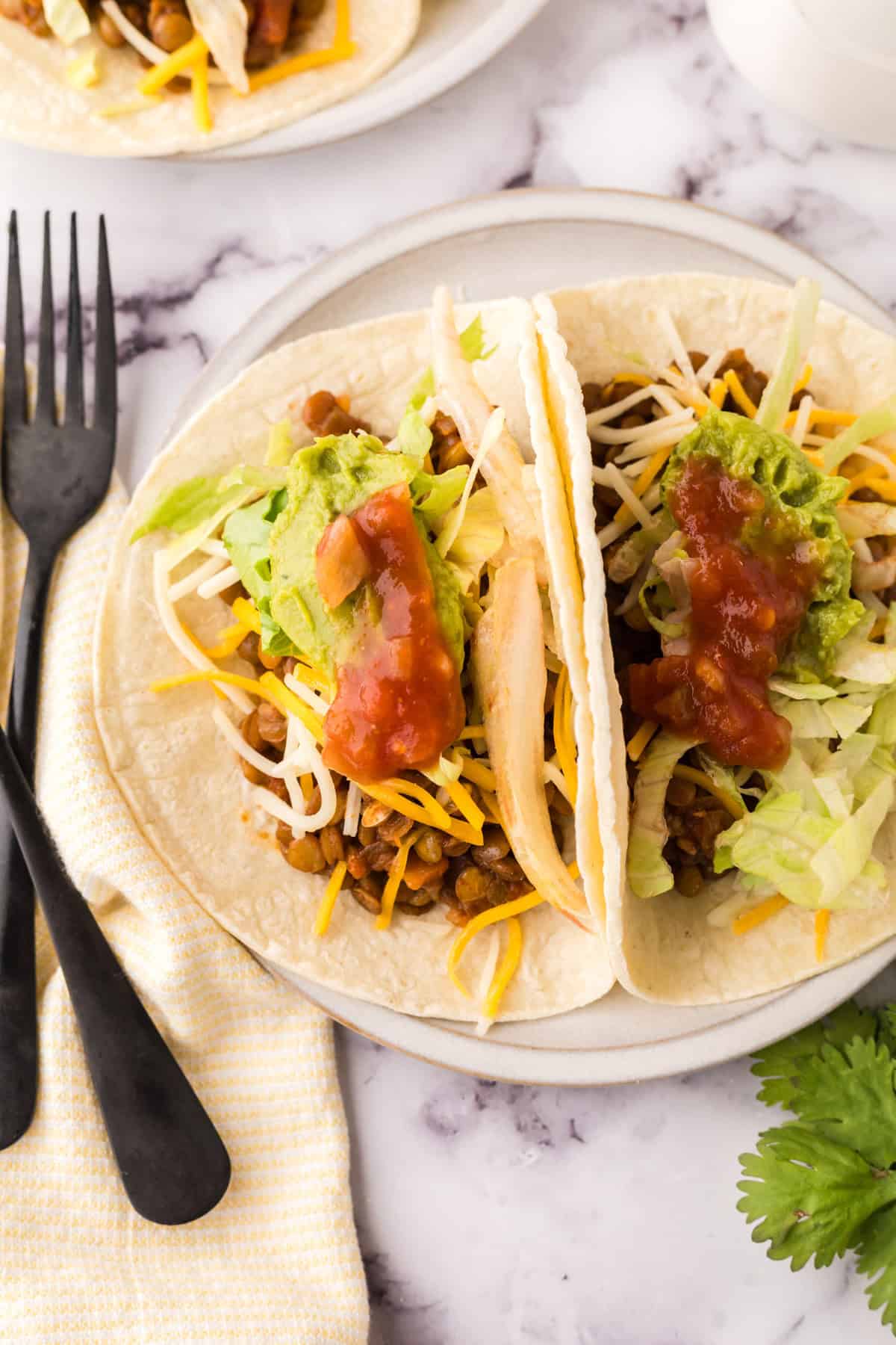 two lentil tacos on a white plate.