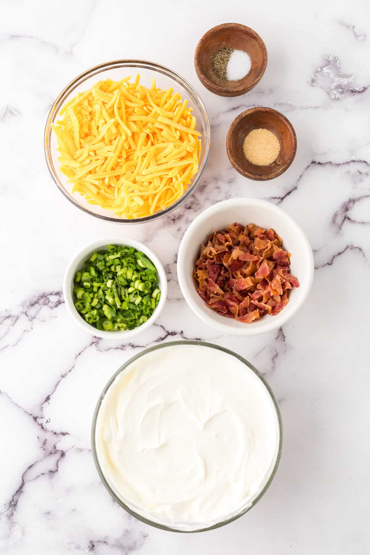 portion bowls each with raw ingredients to make loaded baked potato dip.
