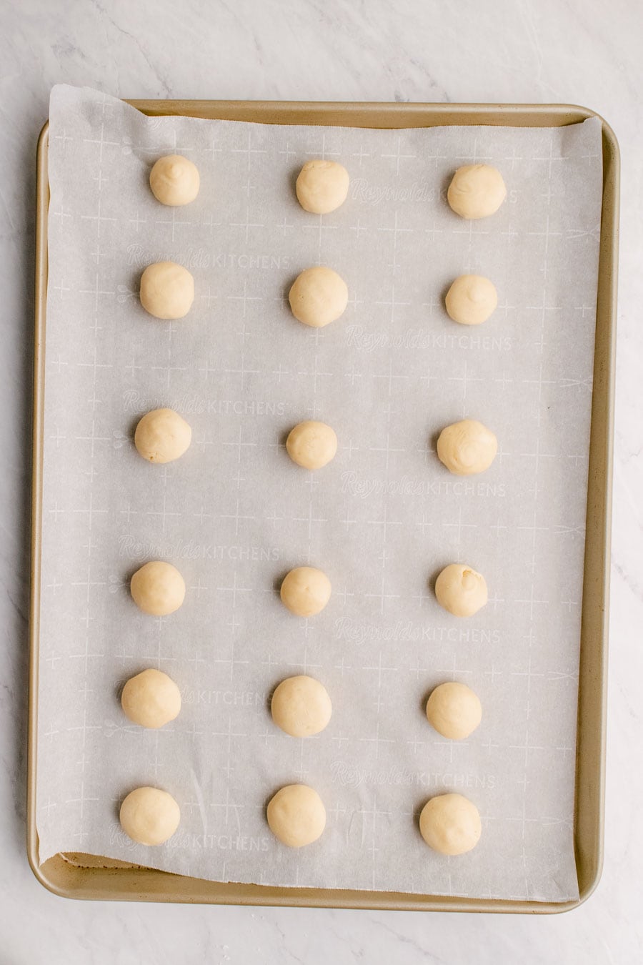 Melt away cookie dough balls on a sheet pan lined with parchment paper ready to bake.