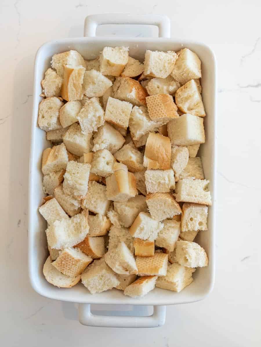 Cubes of French bread in a white baking dish.