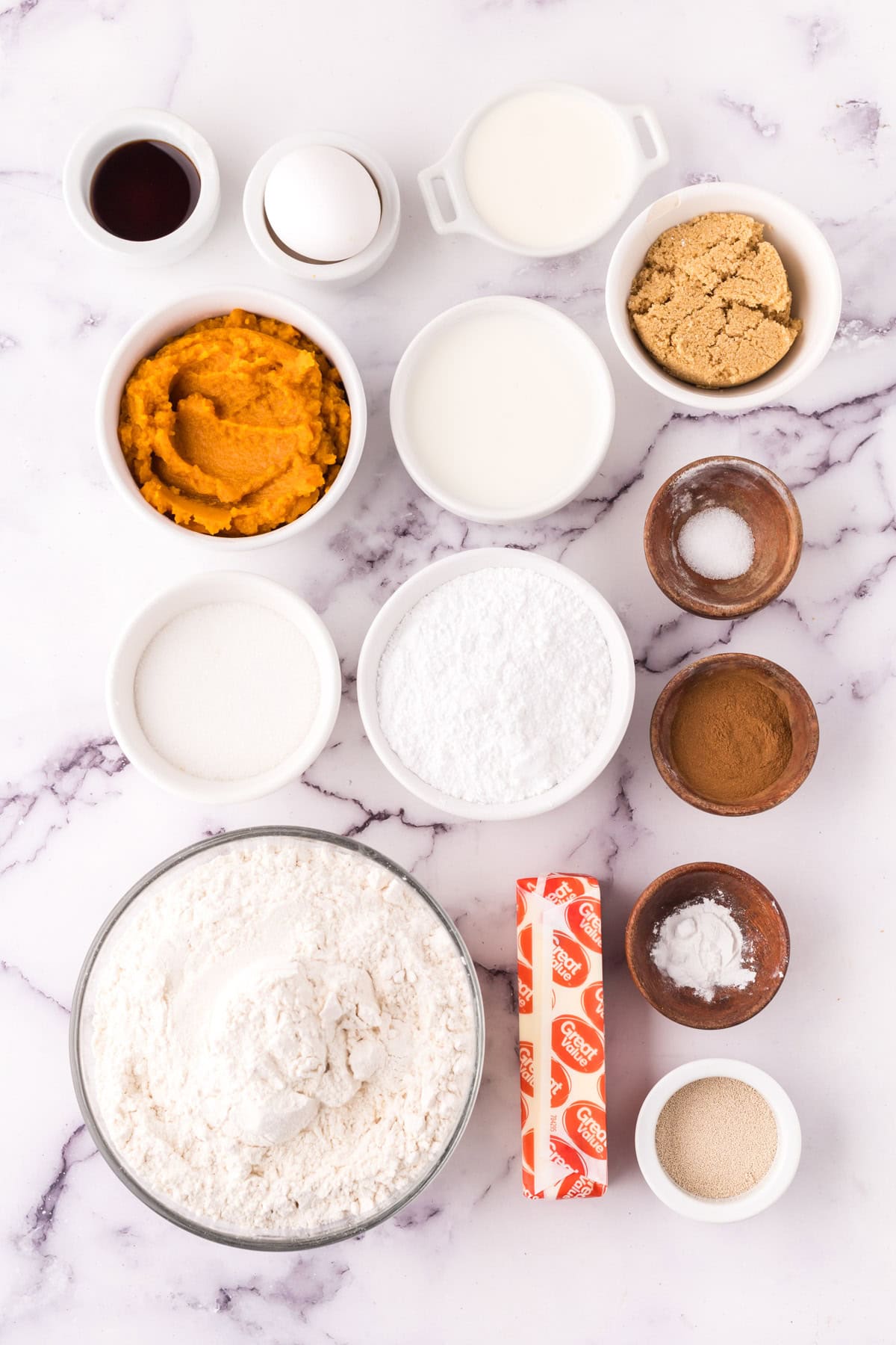 Measured out ingredients for pumpkin cinnamon rolls all in separate bowls.
