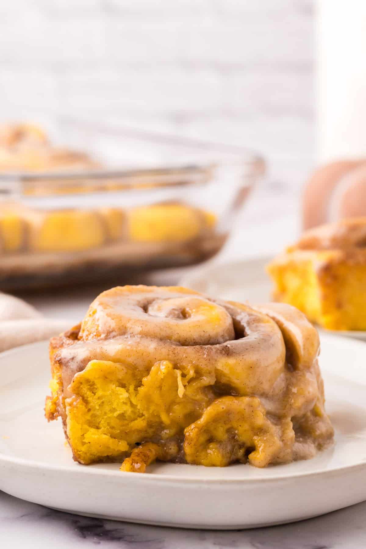 pumpkin cinnamon rolls on round white plates.