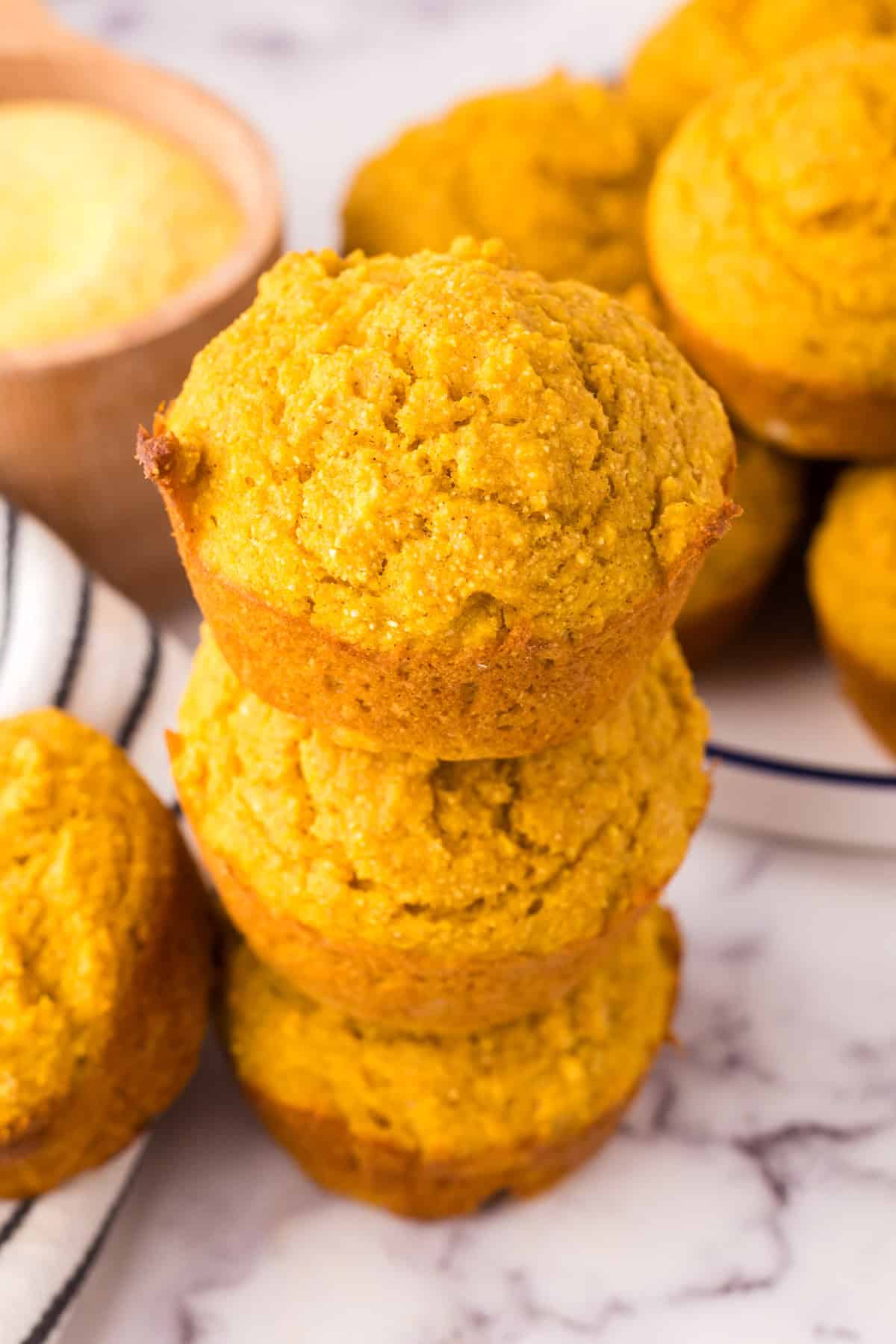 pumpkin cornbread muffins stacked three high.