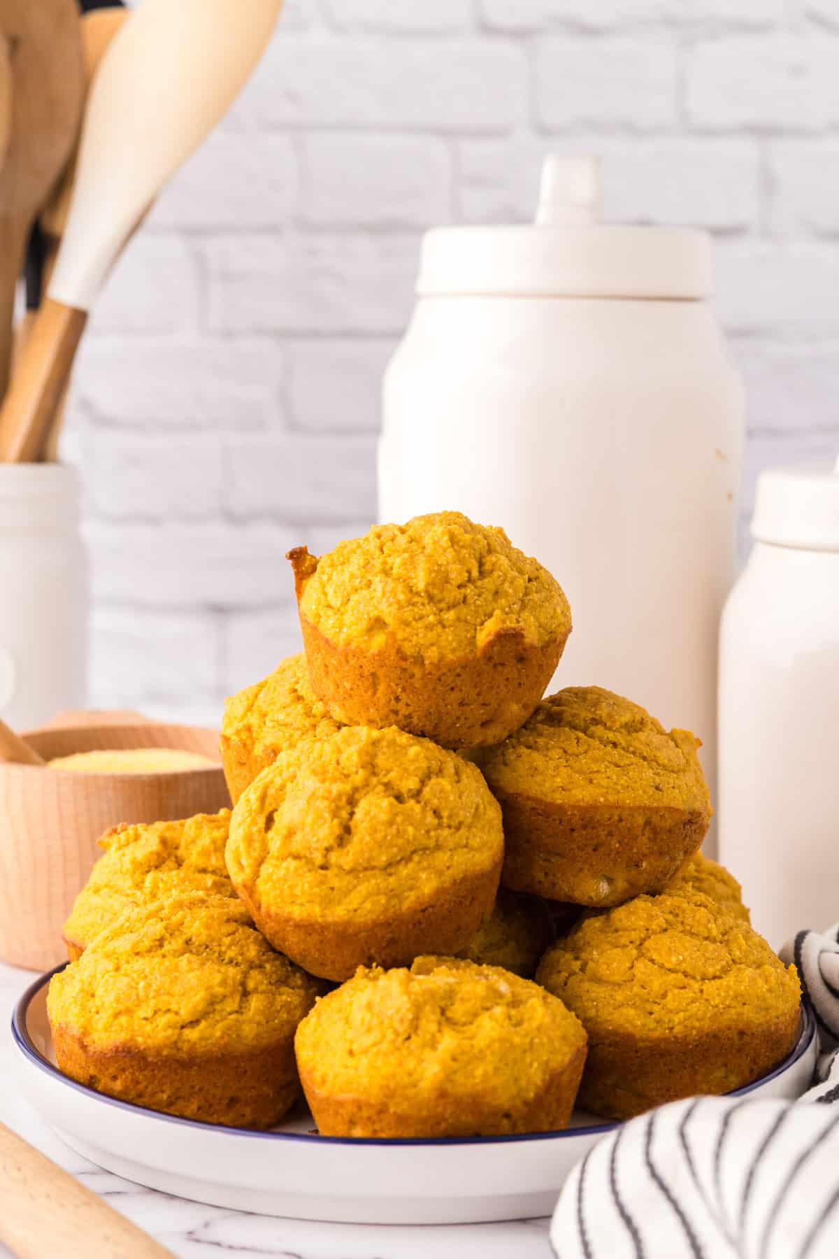 pumpkin cornbread muffins stacked around a round plate.