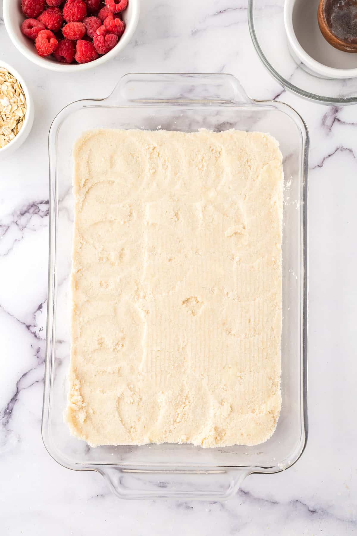 clear glass baking dish in the process of making raspberry streusel bars.