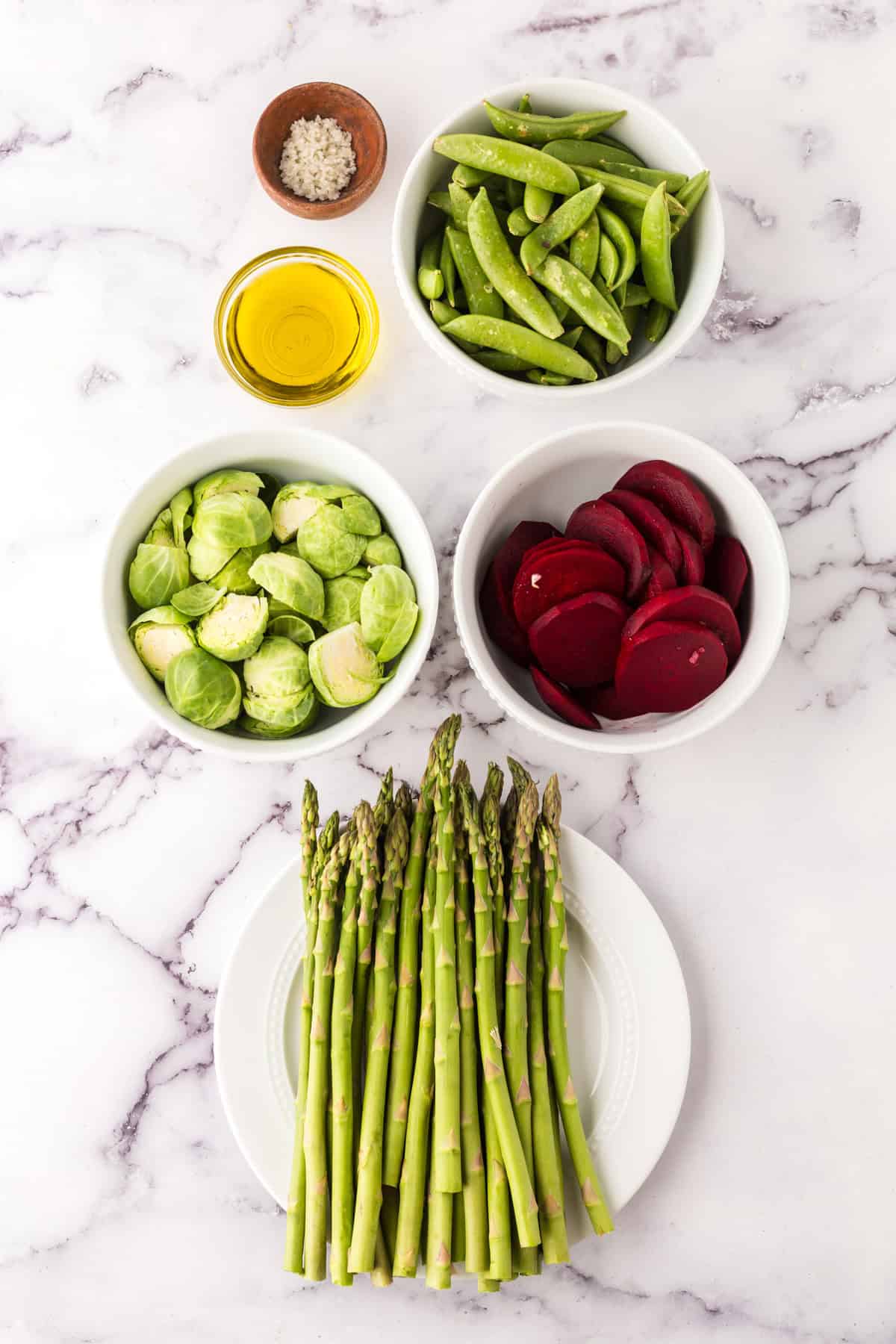 portion bowls each with raw ingredients to make roasted spring vegetables.