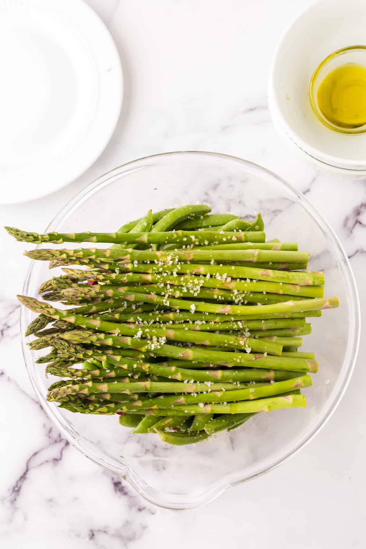 clear mixing bowl in the process of making roasted asparagus.
