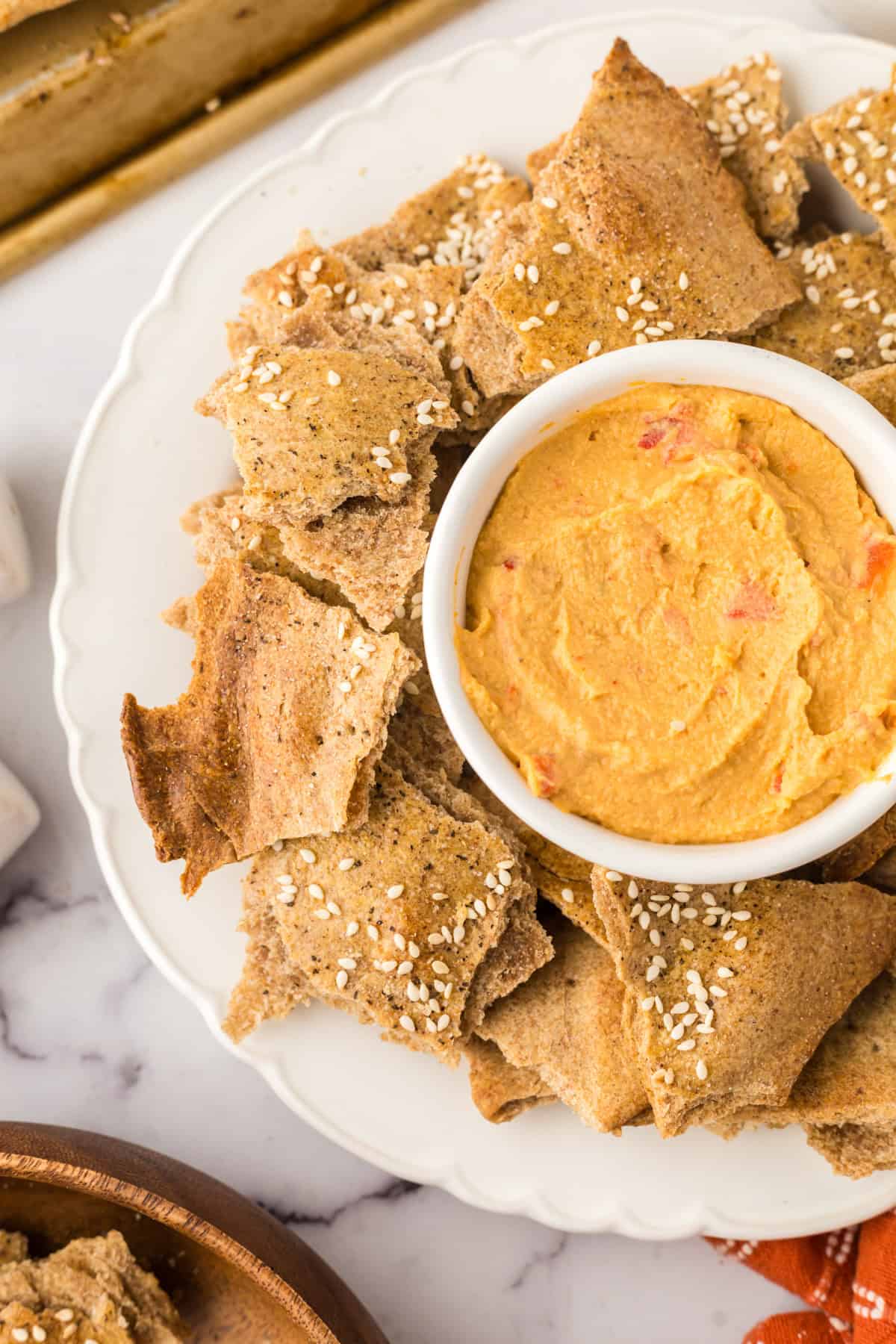 simple lavish bread crackers on a round plate with a bowl of dip in the middle.