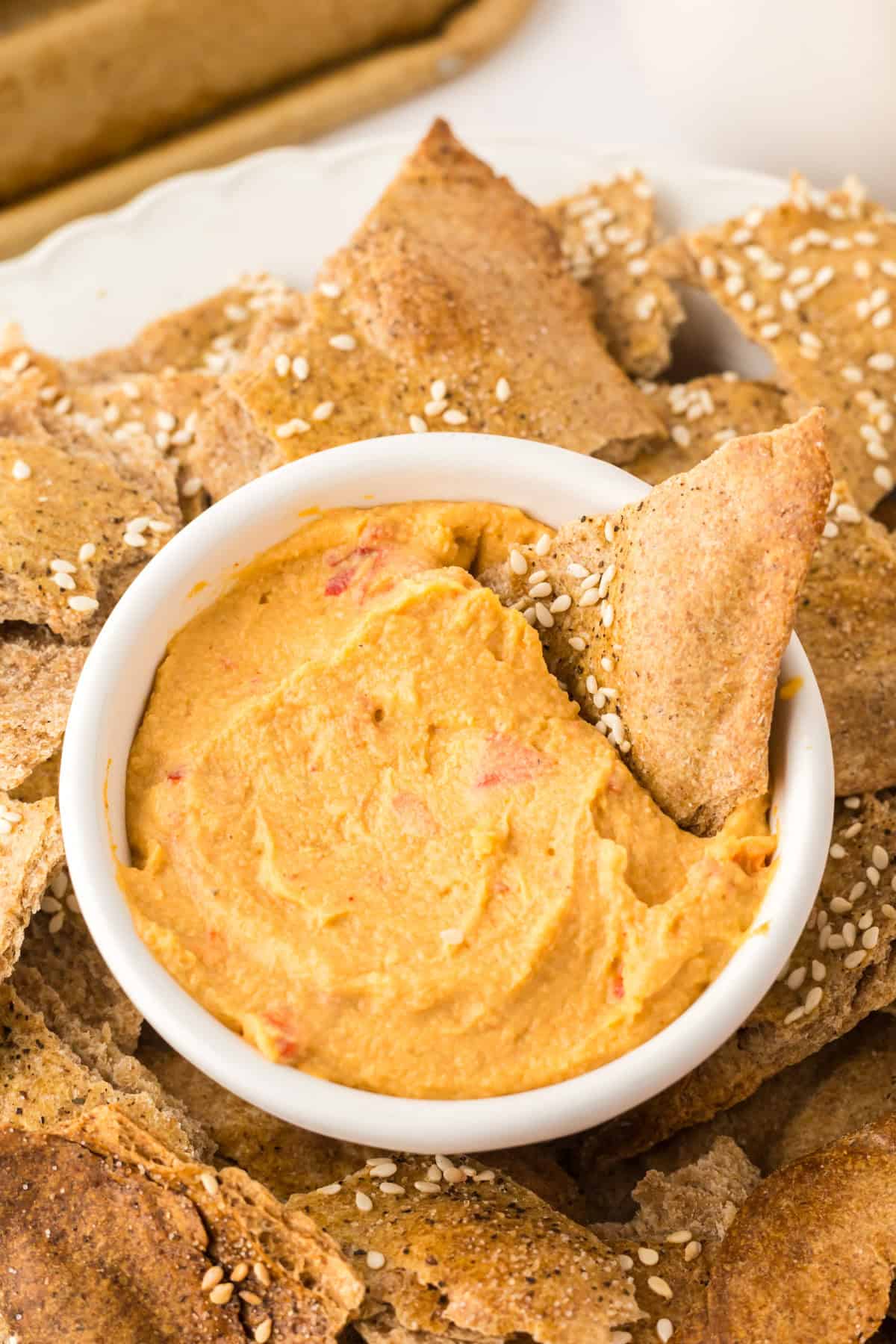 simple lavish bread crackers on a round plate with a bowl of dip in the middle.