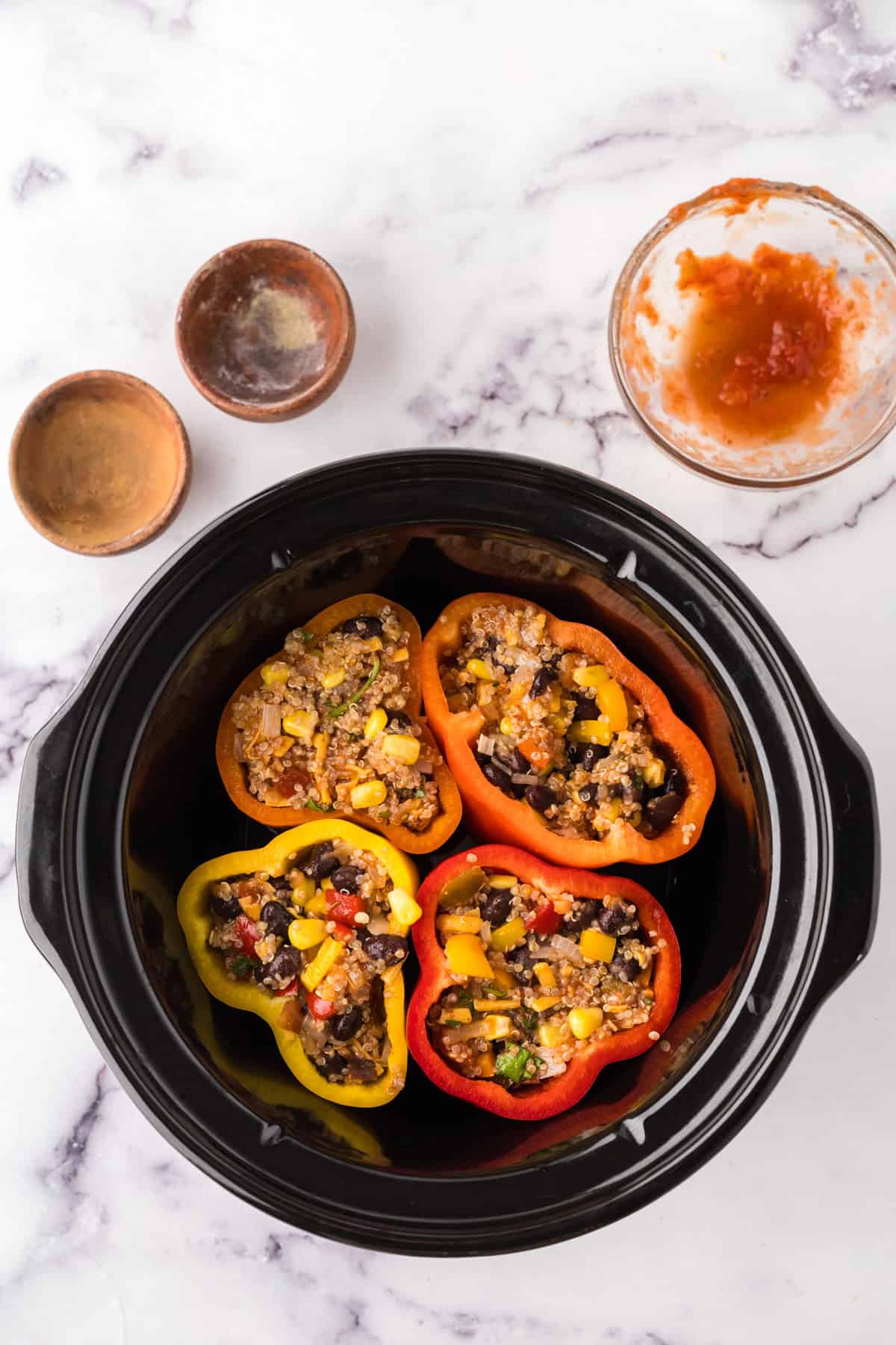 slow cooker bowl with four halved stuffed bell peppers.
