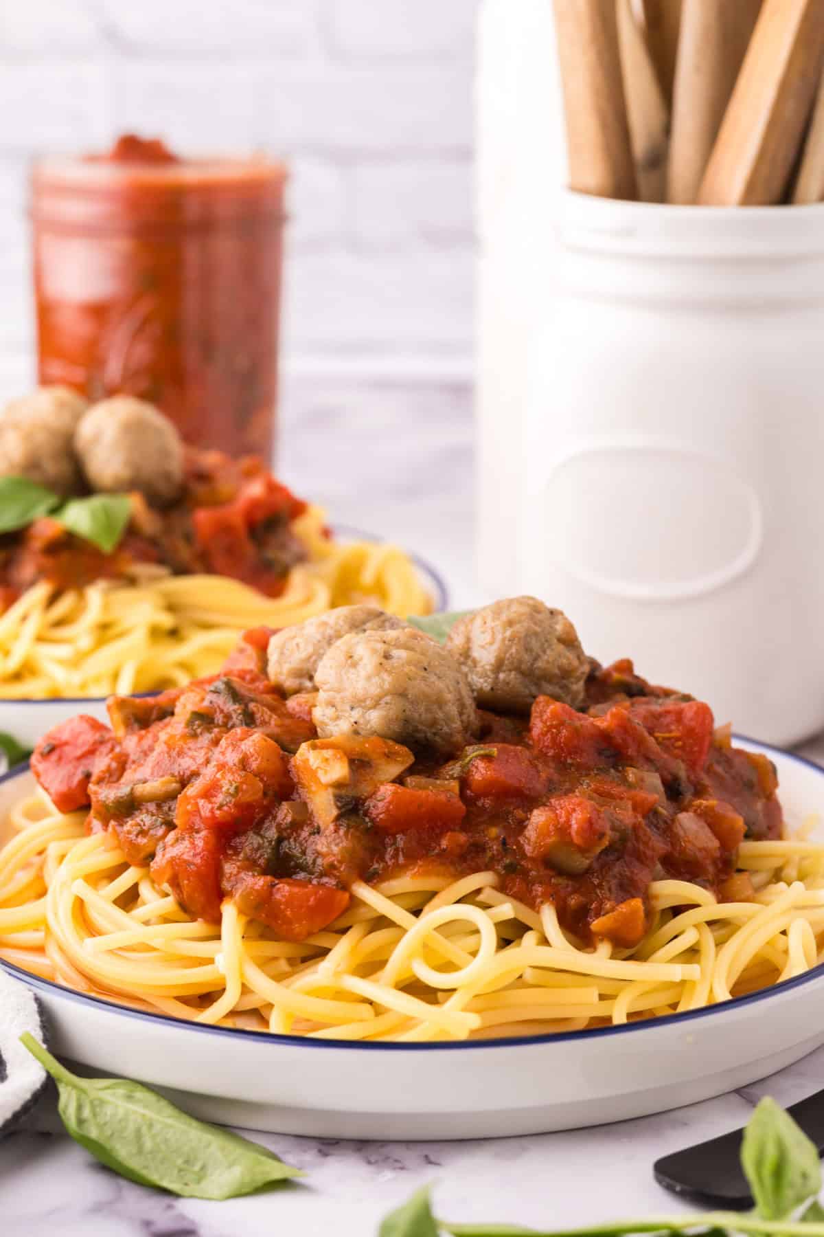 spinach mushroom marinara on a round plate of pasta with meatballs on top.