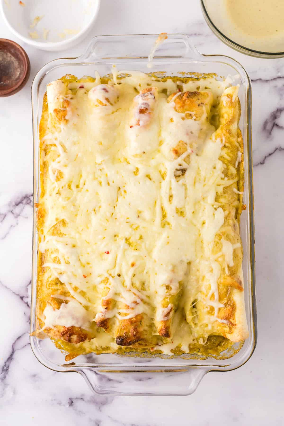 cheesy and gooey tomatillo ranch burritos in a clear casserole dish.