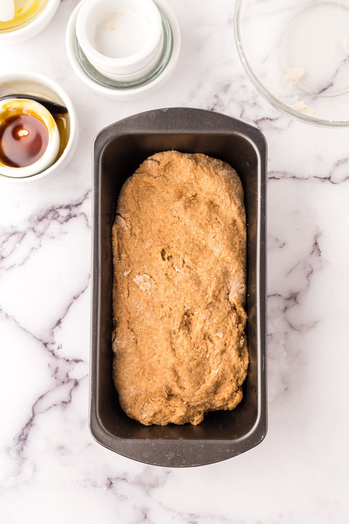 bread tin with raw dough in the process of making wheat bread recipe.