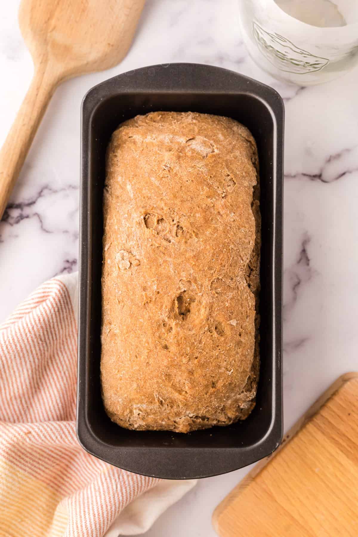 bread tin with baked dough in the process of making wheat bread recipe.