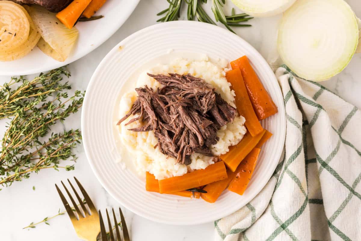 slow cooker pot roast dinner on a round white plate.
