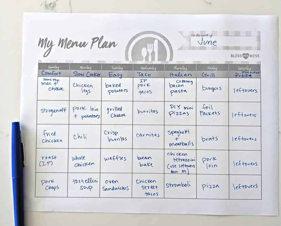 An easy weekly meal plan for June is handwritten and organized by meal types (Comfort, Slow Cooker, Easy, Taco, Italian, Grill, Leftovers), with dishes listed for each day on a white surface and a blue pen nearby.