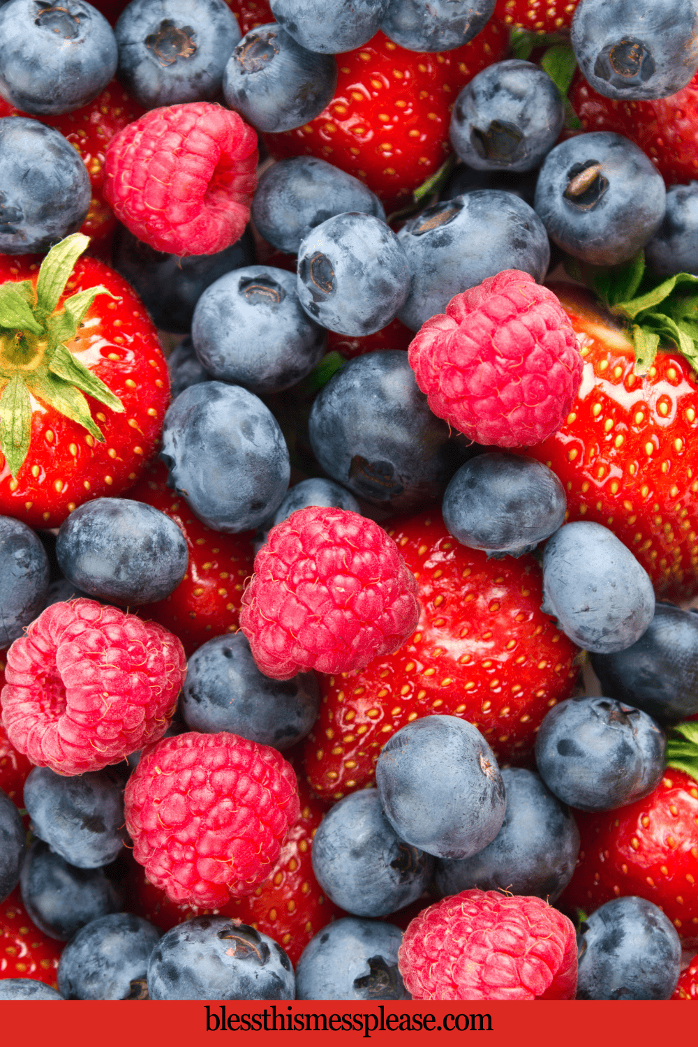 A close-up of fresh strawberries, blueberries, and raspberries piled together, showing their vibrant red and blue colors and juicy textures. The website appears at the bottom.
