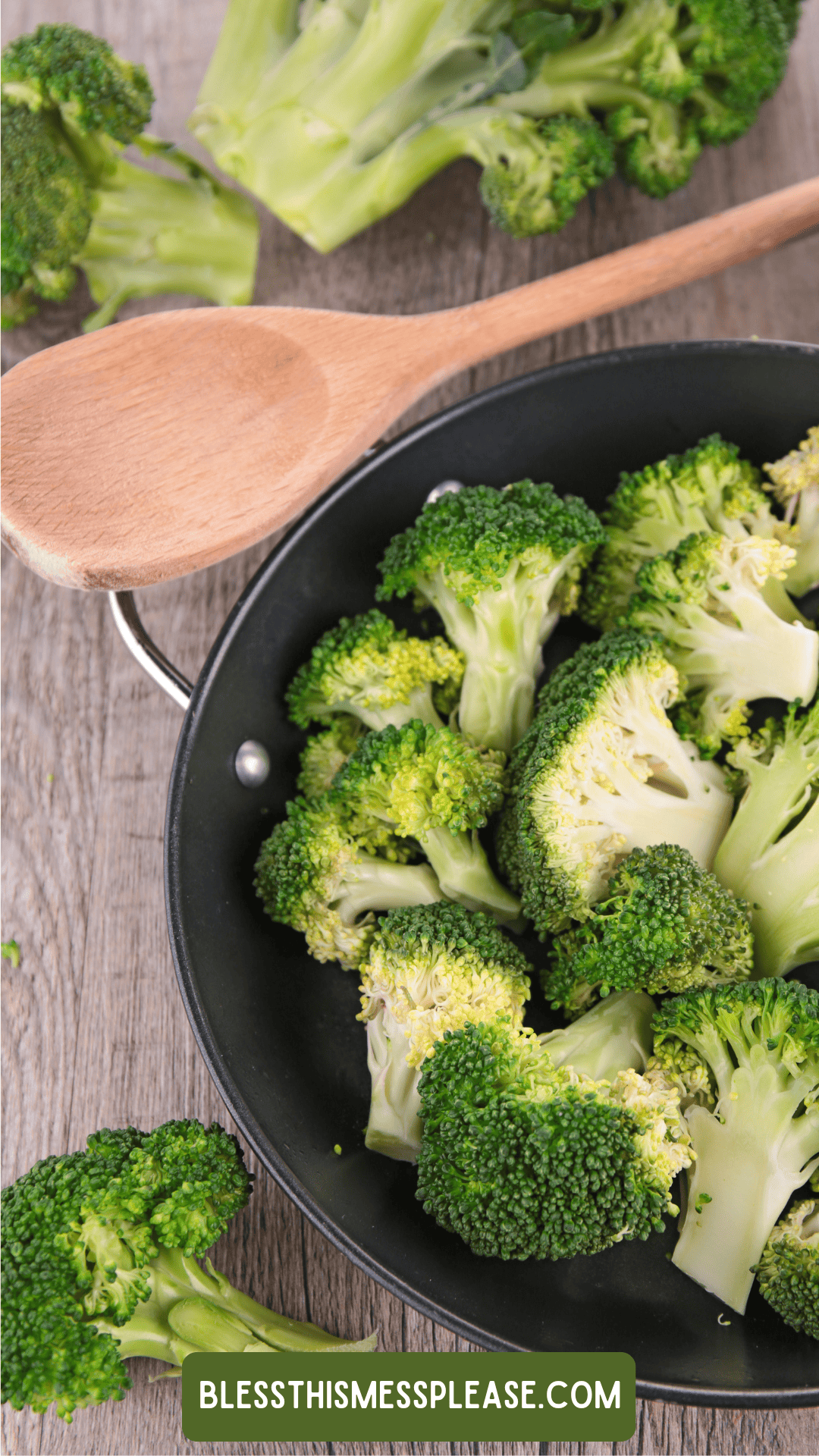A frying pan filled with fresh broccoli florets sits on a wooden surface next to a wooden spoon, with more broccoli for how to preserve broccoli and a website label visible.