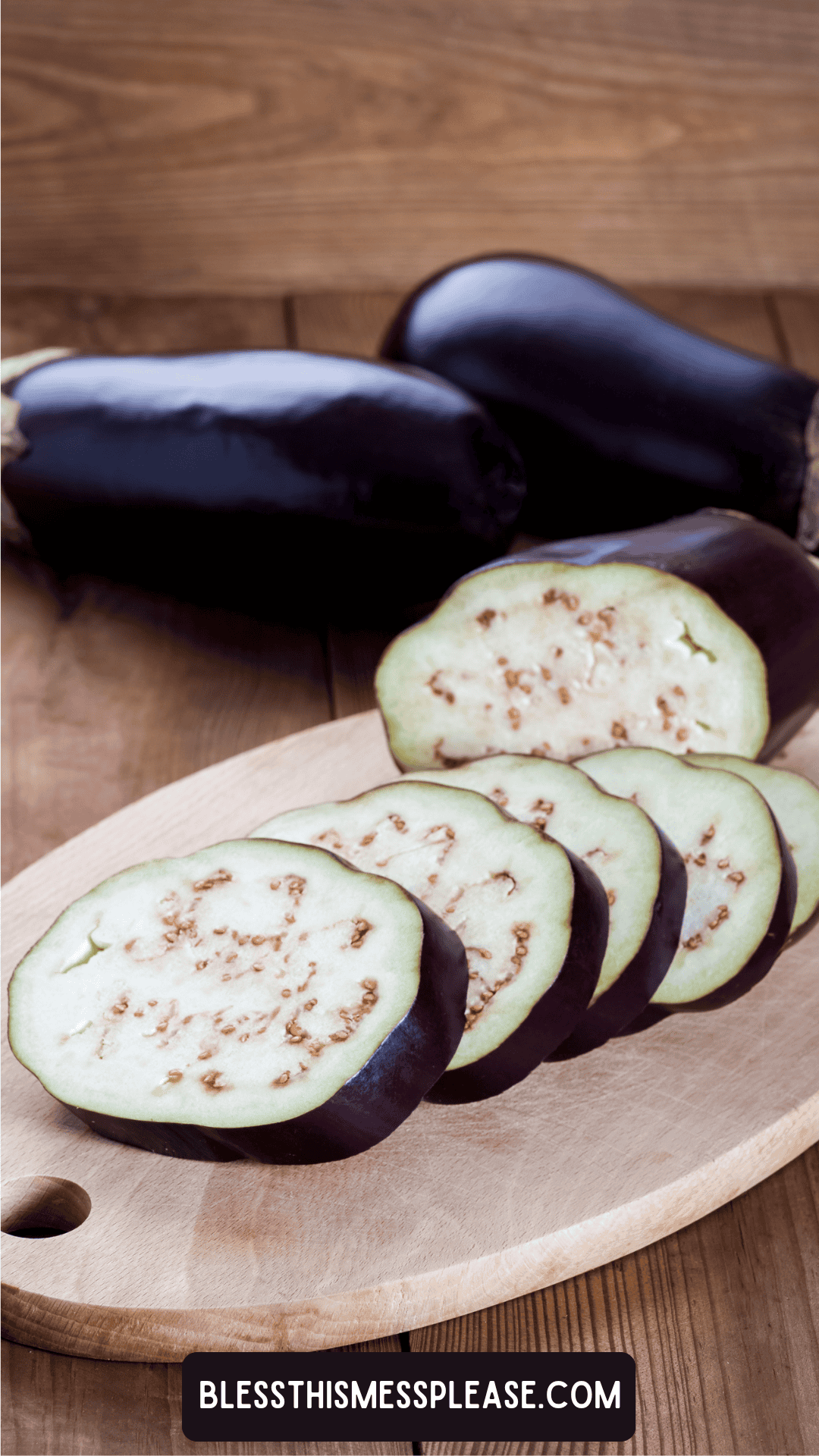 A close-up of sliced eggplant on a wooden cutting board, with two whole eggplants in the background. The website is printed on the bottom edge, perfect for illustrating how to preserve eggplant.