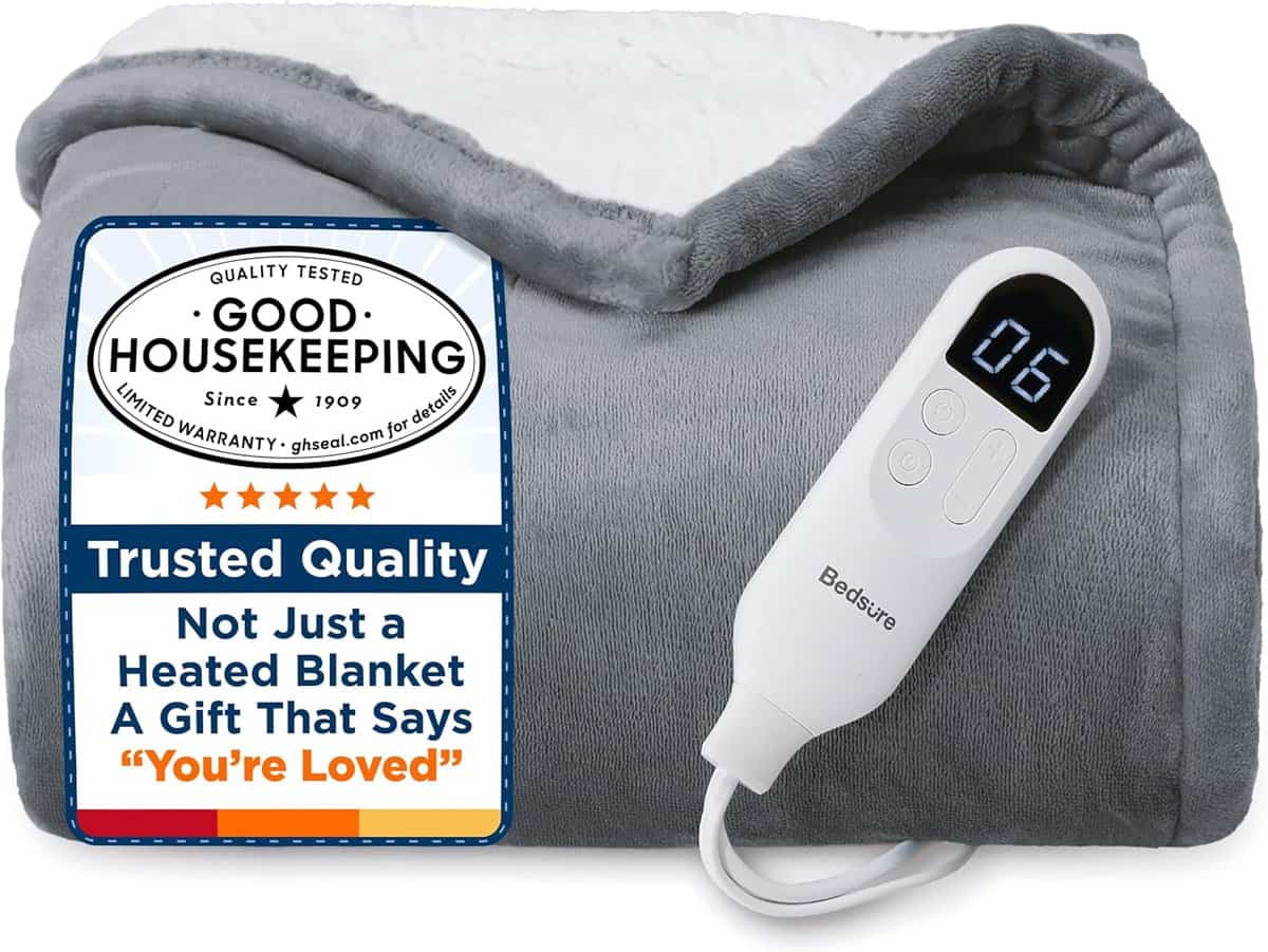 A folded gray heated blanket with a white controller displaying 06, next to a label that reads: Good Housekeeping, Trusted Quality, and Not Just a Heated Blanket, A Gift That Says You’re Loved.
