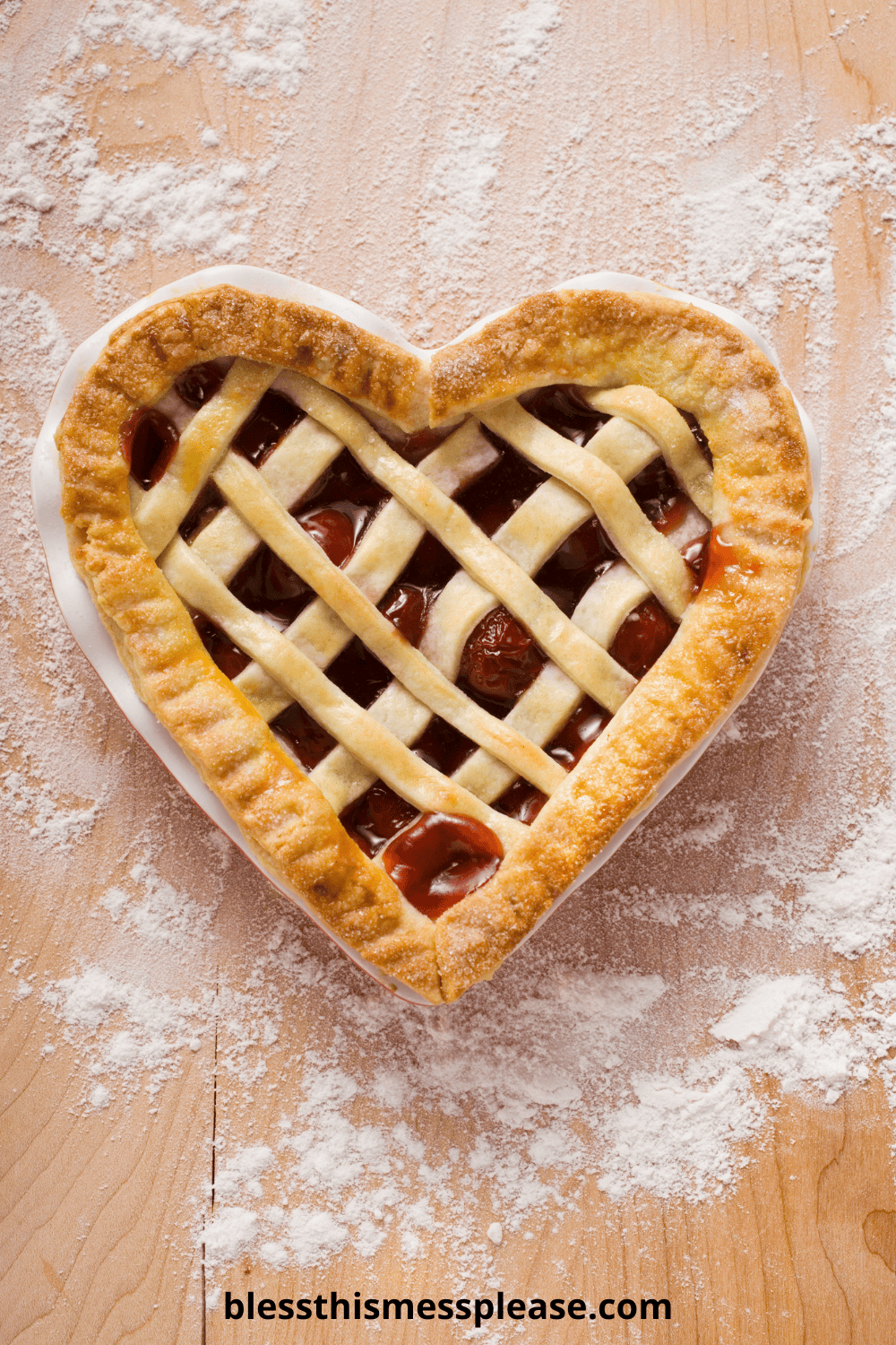 A heart-shaped cherry pie with a lattice crust sits on a floured wooden surface. The golden brown edges and peek of cherry filling hint at homemade goodness—learn how to make pie crust at